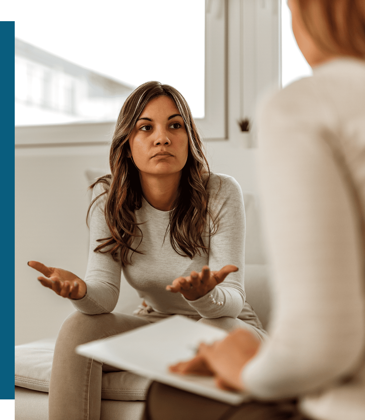 A woman expressing frustration during a conversation with another person.