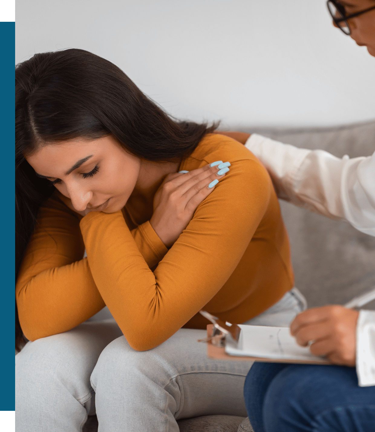 A woman receives comforting support from a person during a counseling session.