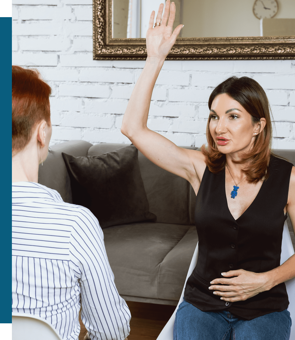 A woman raising her hand while talking to a man on a couch.