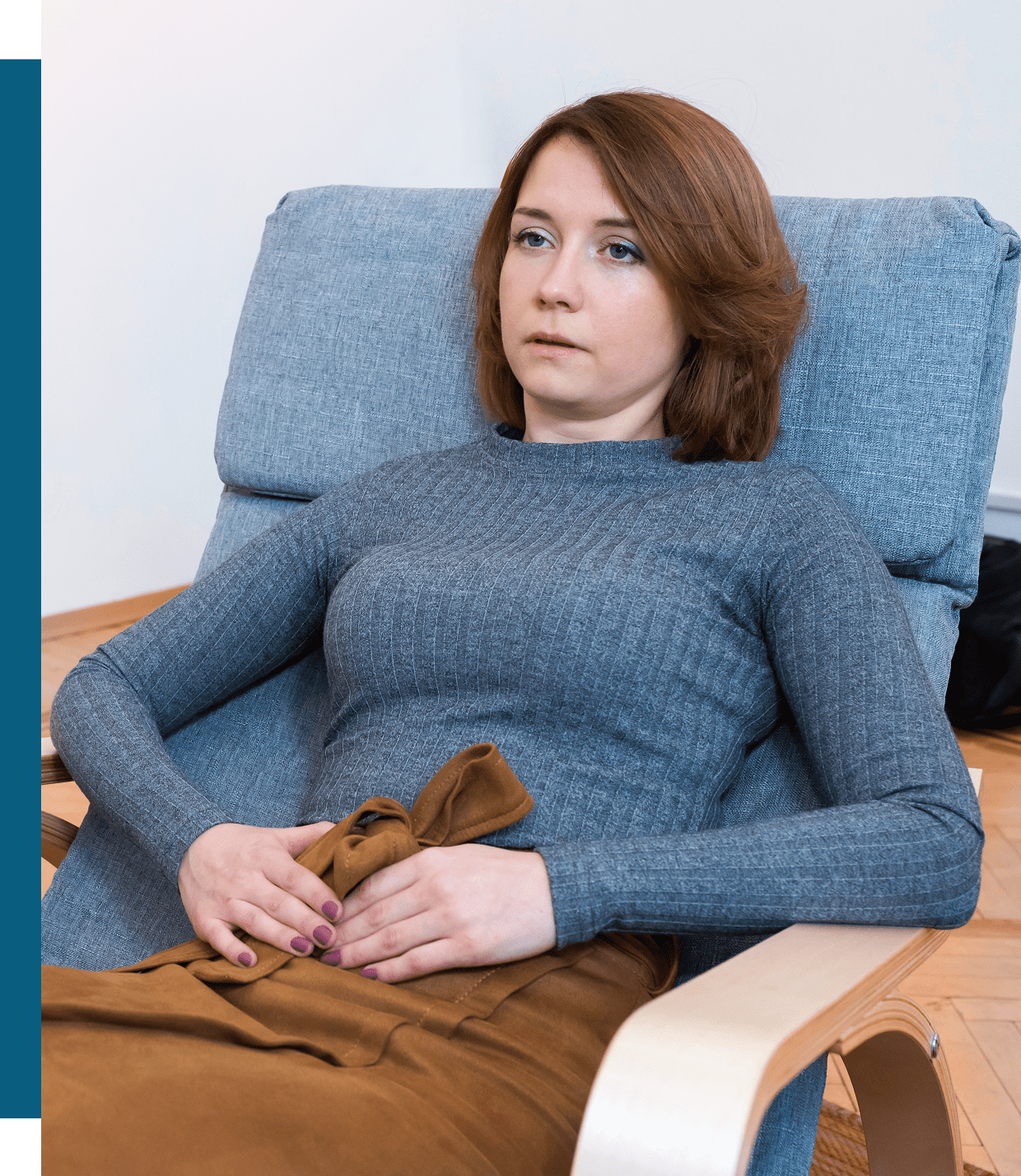 A woman relaxing on a chair holding a hot water bottle.