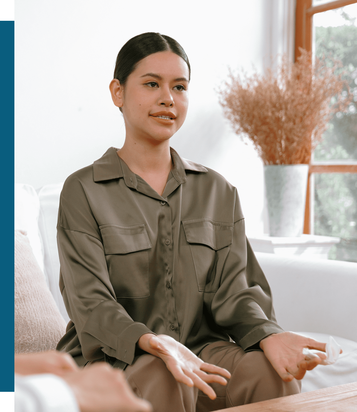 Woman sitting on a couch, looking relaxed and thoughtful.