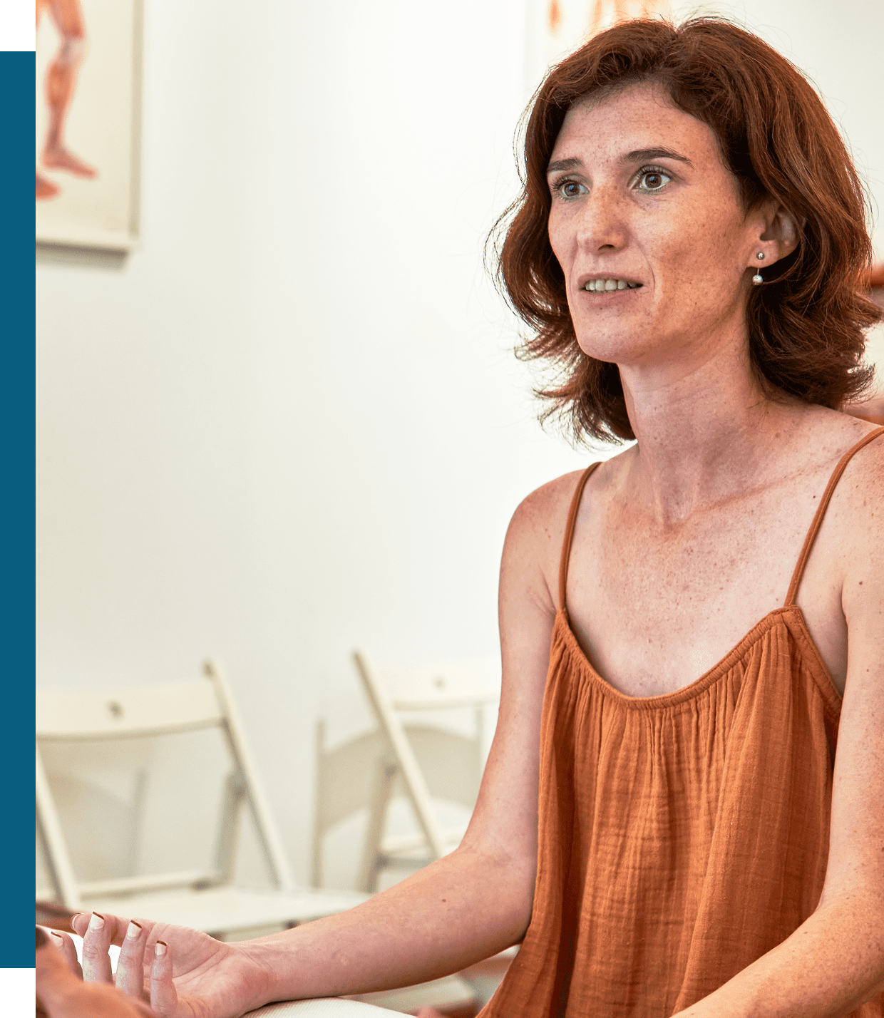 Woman in a rust-colored sleeveless top speaking indoors.